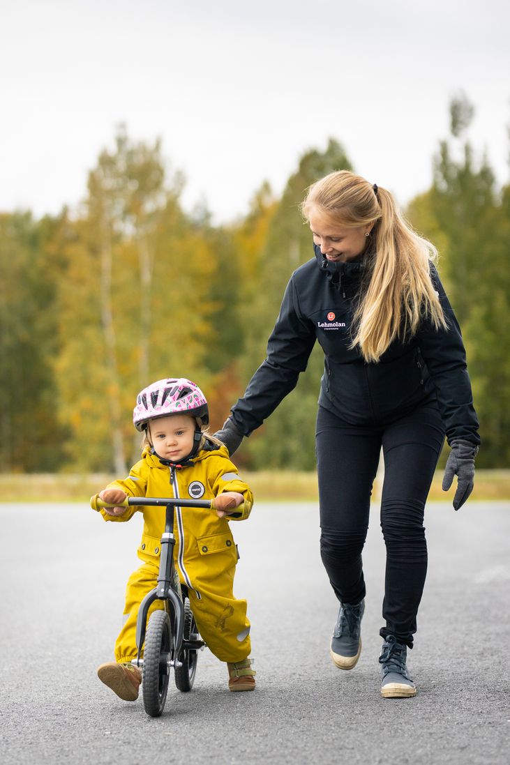 Fysioterapeutti harjoittelemassa pyöräilyä potkupyörällä lapsen kanssa